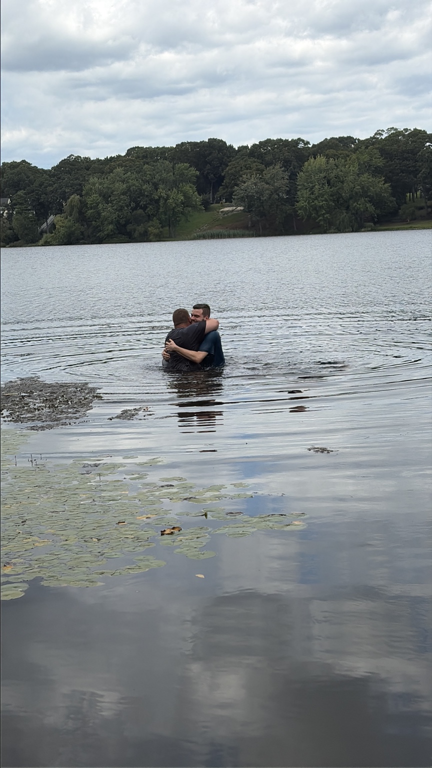 Two people embrace in the water at a Living Faith baptism