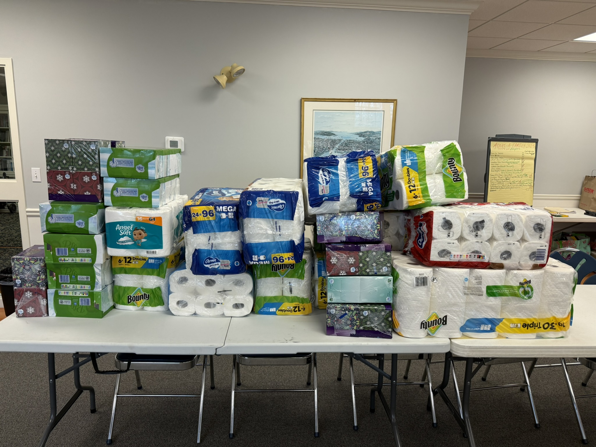 Paper towels, tissues, and toilet paper stacked across tables at Living Faith Pantry