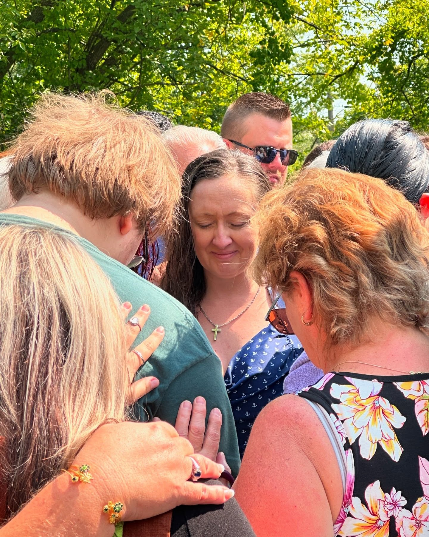 Church members gathered closely around a woman in blue, praying with hands resting on one another