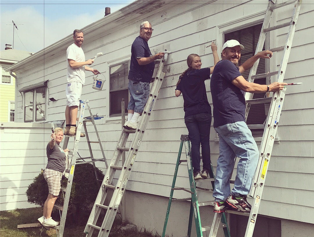 Living Faith volunteers painting together on ladders