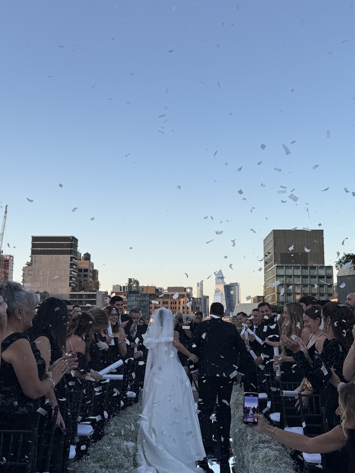 Guests celebrate a newly married couple with confetti outdoors