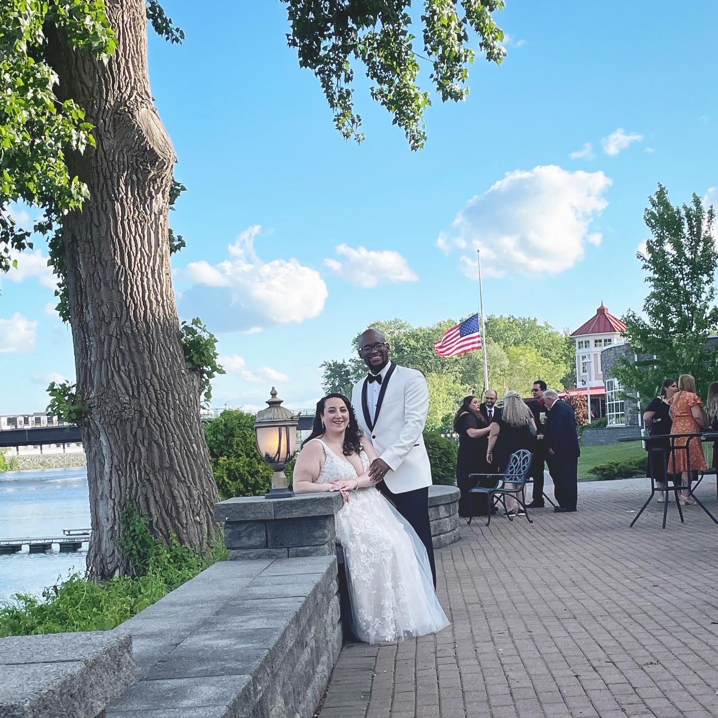 A bride and groom smile together beside the water
